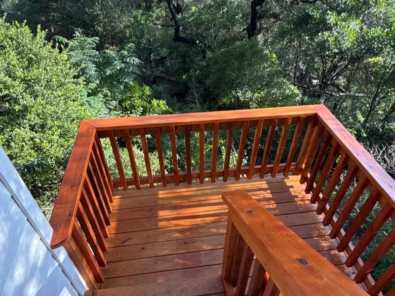 Wood deck with railing above a tree line