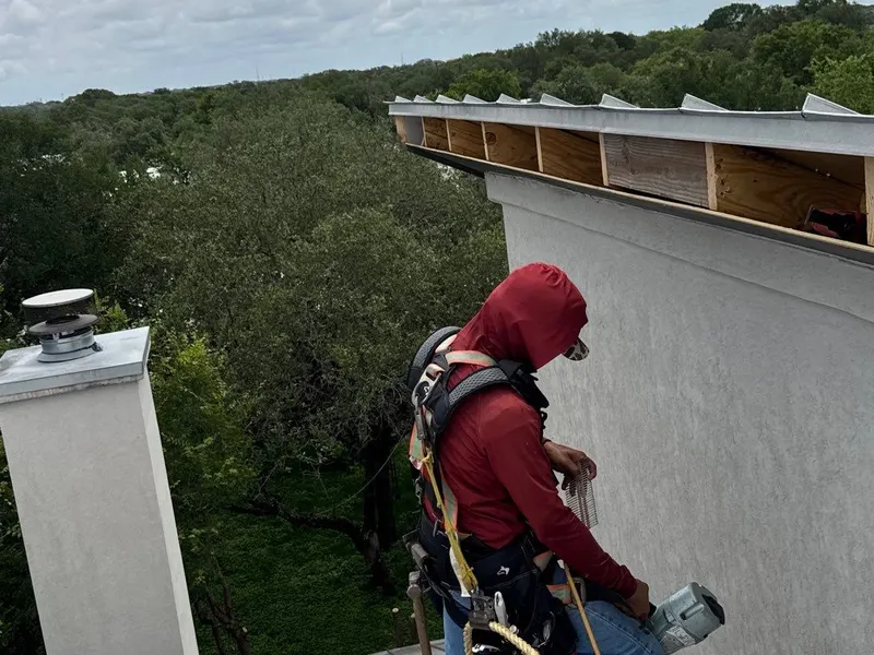 Roofer in a safety harness at a roofline